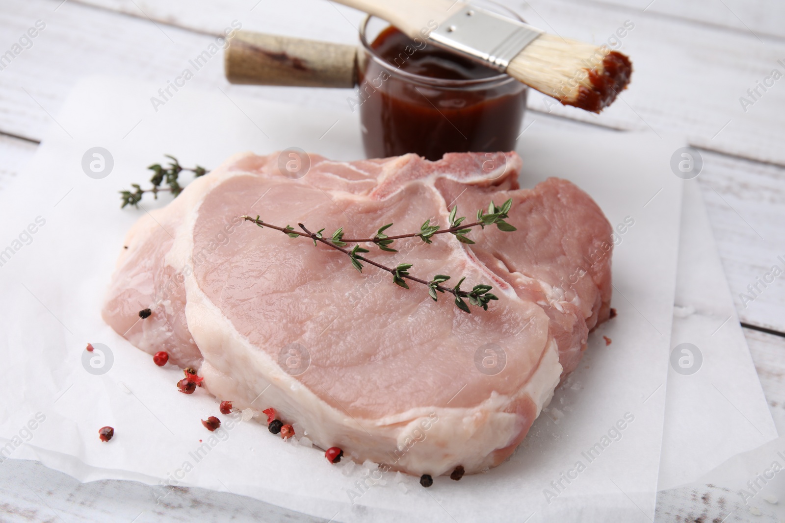 Photo of Raw meat, thyme, spices and marinade on white wooden table, closeup