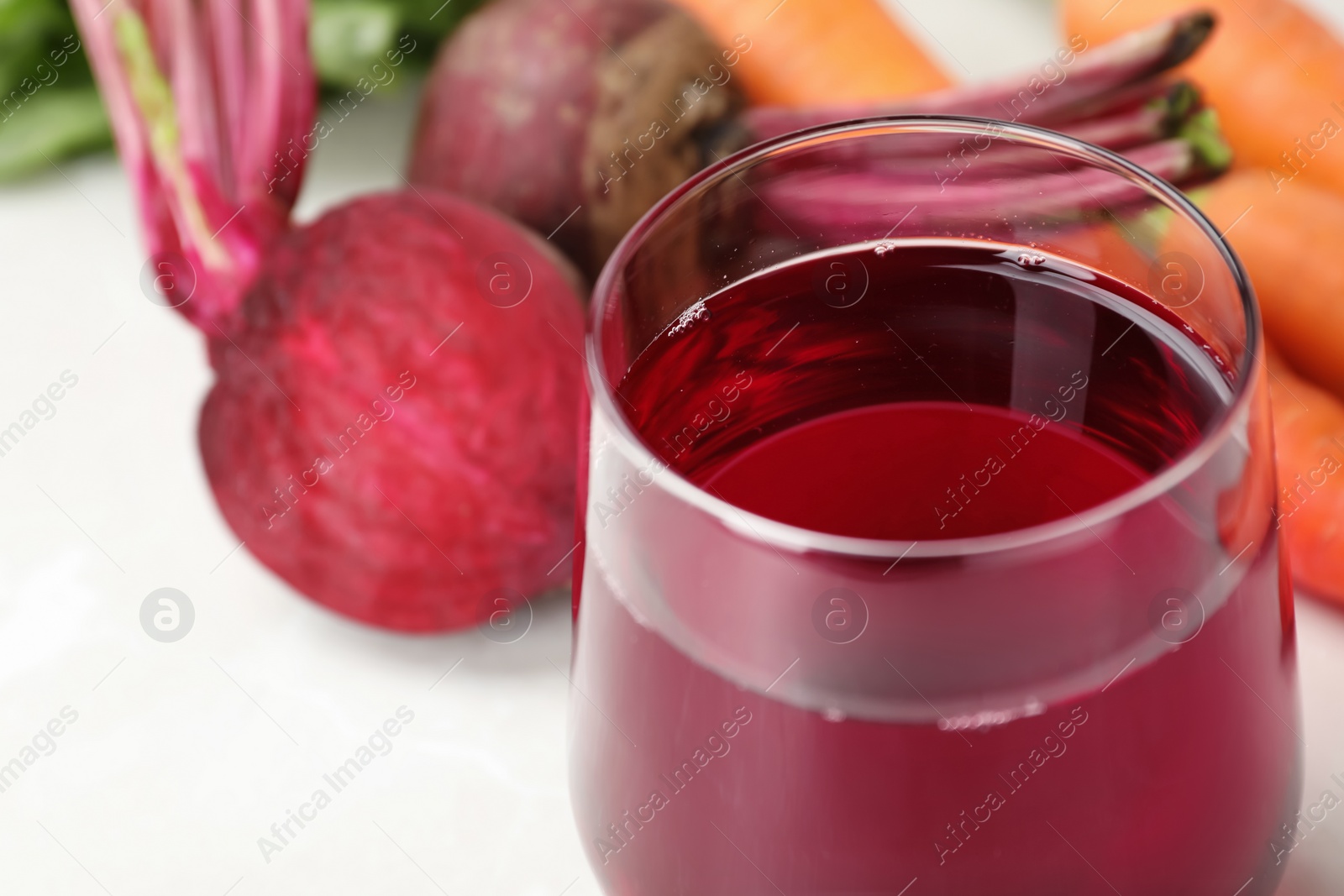 Photo of Glass with fresh beet juice on table, closeup