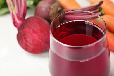 Photo of Glass with fresh beet juice on table, closeup