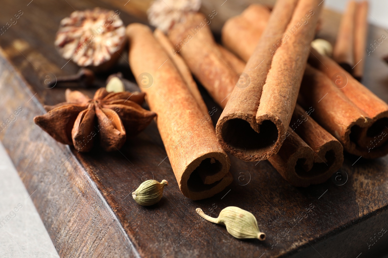 Photo of Board with different aromatic spices on light table, closeup