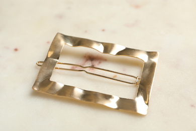 Photo of Beautiful gold hair clip on marble table, closeup