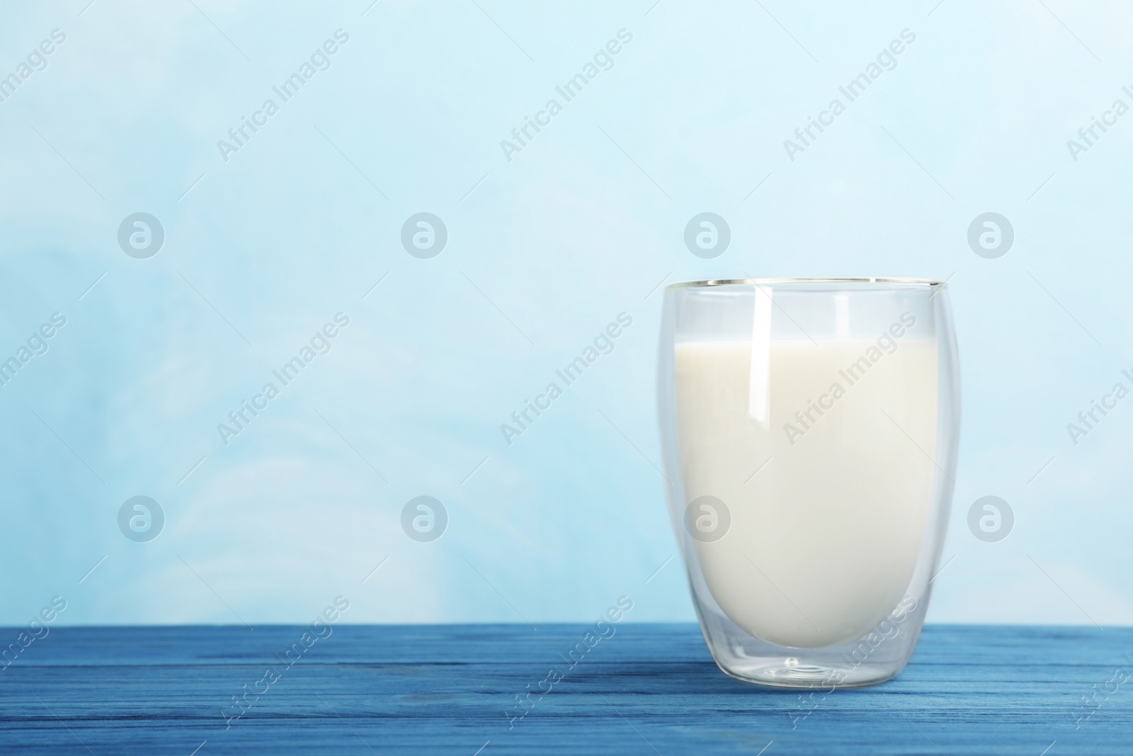 Photo of Glass with fresh milk on table against color background. Space for text