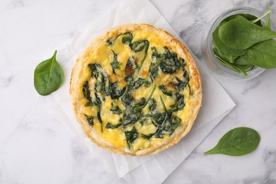 Photo of Delicious pie with spinach on white marble table, flat lay