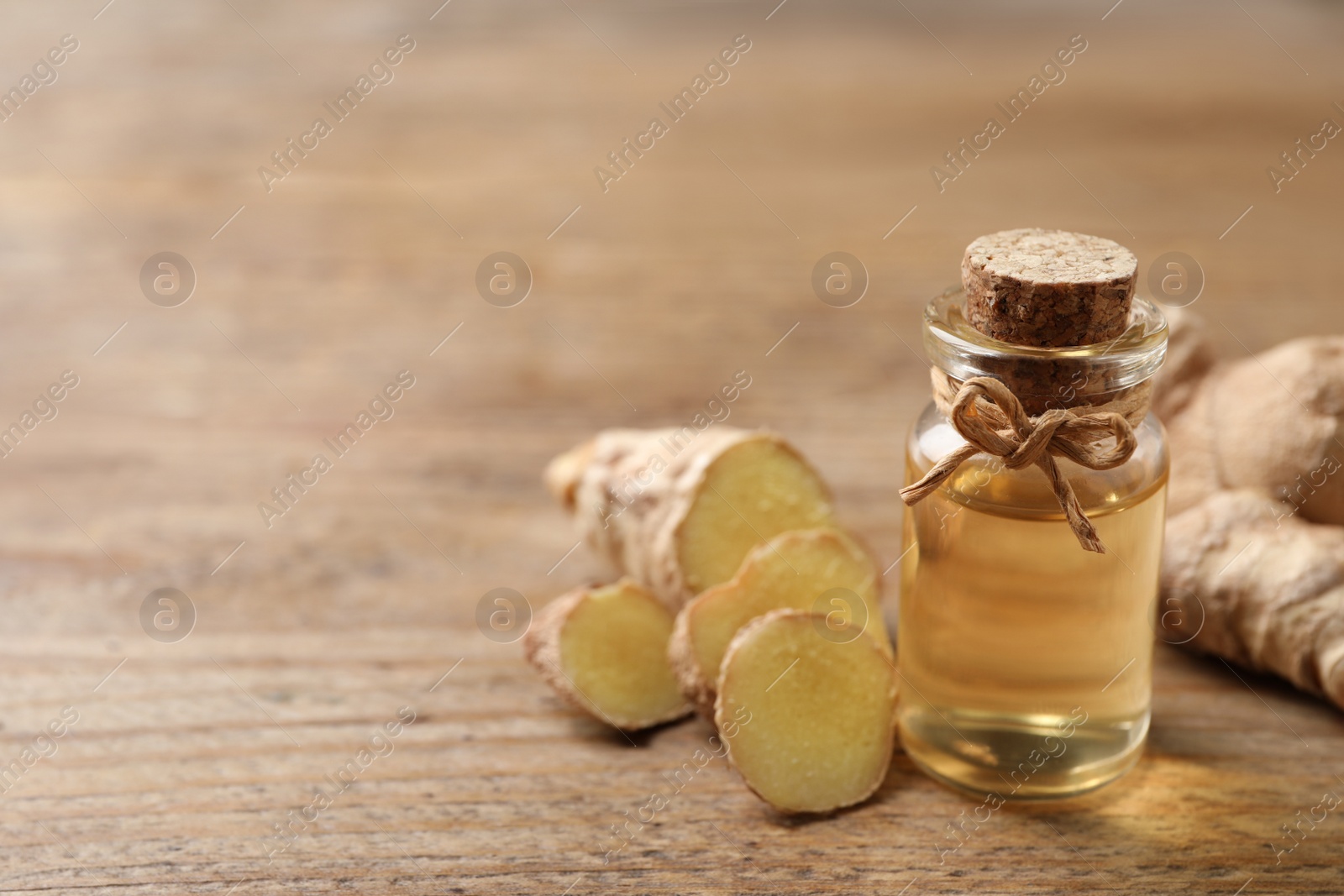 Photo of Ginger essential oil in bottle on wooden table. Space for text