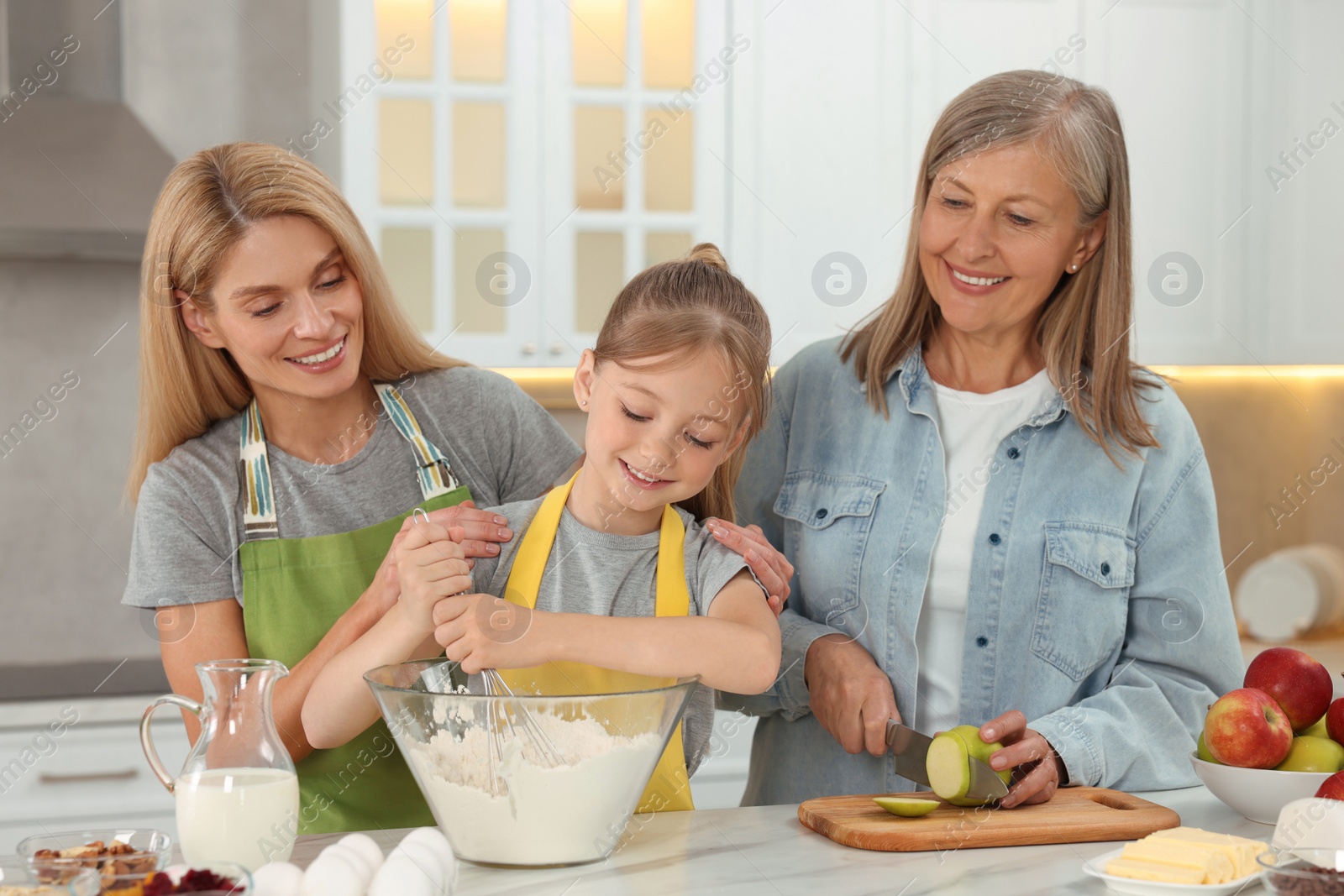 Photo of Three generations. Happy grandmother, her daughter and granddaughter cooking together in kitchen