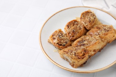 Photo of Eastern sweets. Pieces of tasty baklava on white tiled table. Space for text