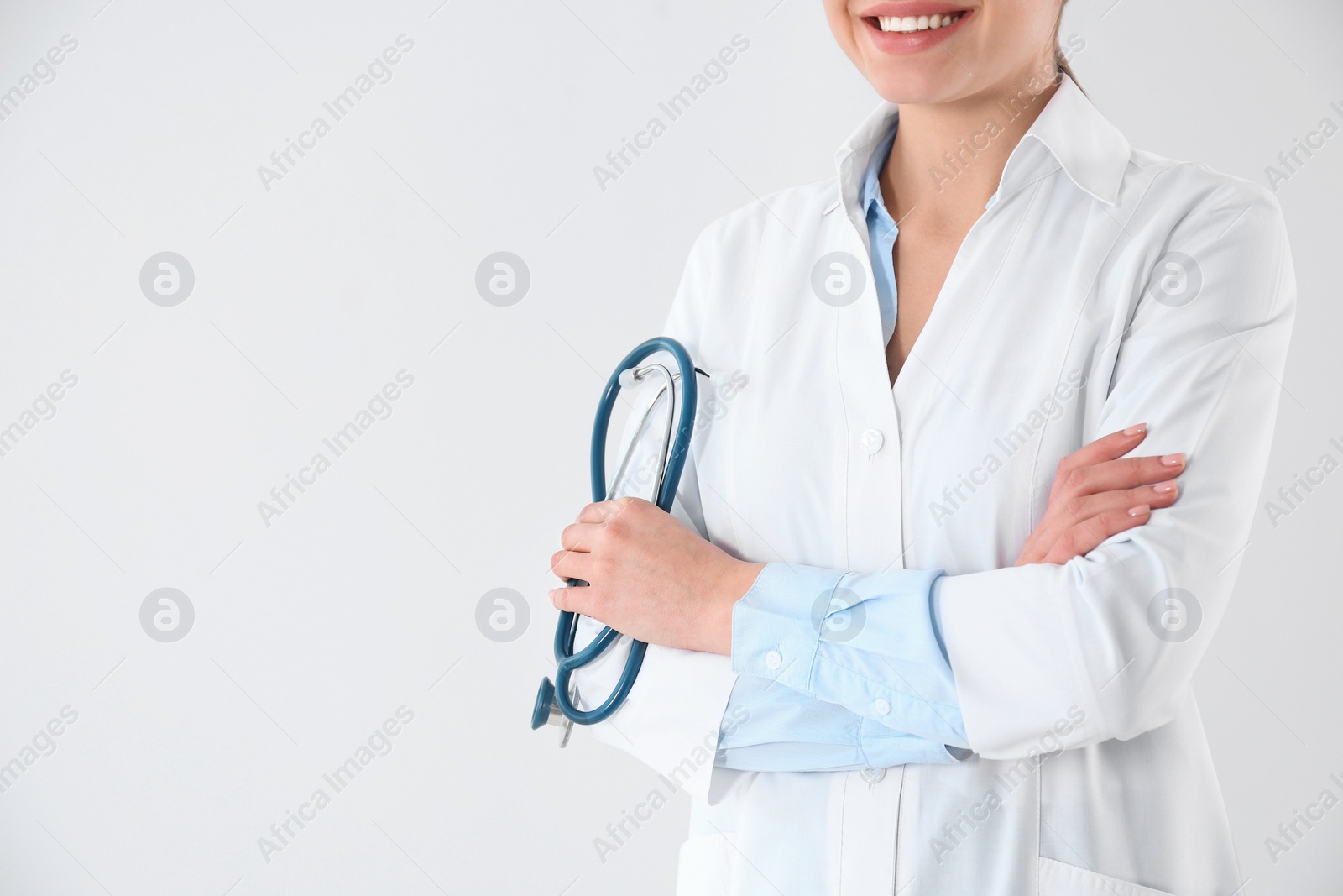 Photo of Young doctor with stethoscope on white background, closeup