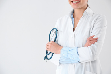 Young doctor with stethoscope on white background, closeup