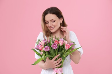 Photo of Happy young woman with bouquet of beautiful tulips on pink background