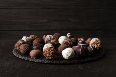 Photo of Different tasty chocolate candies on black table