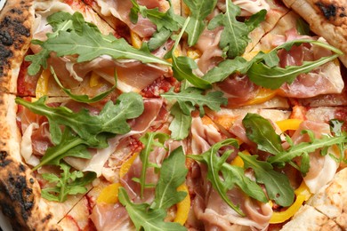 Photo of Tasty pizza with meat and arugula as background, top view