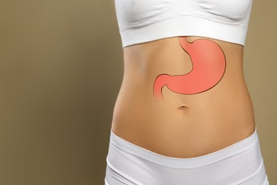 Woman with image of healthy stomach on beige background, closeup. Space for text