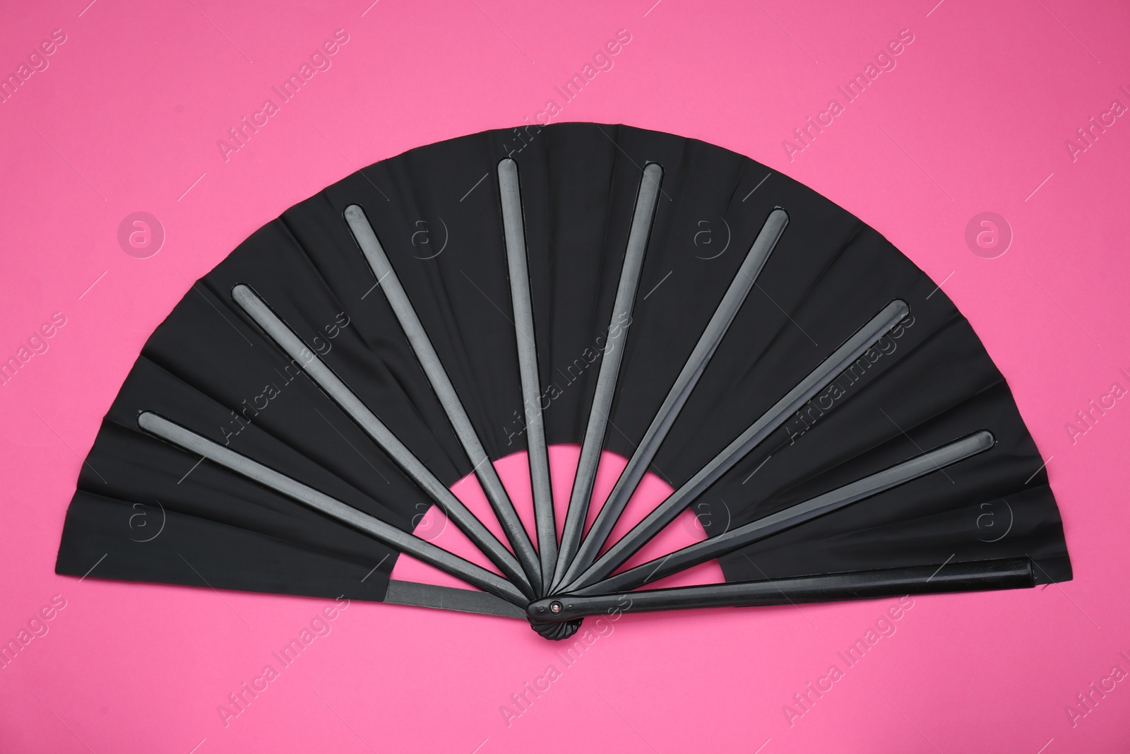 Photo of Stylish black hand fan on pink background, top view