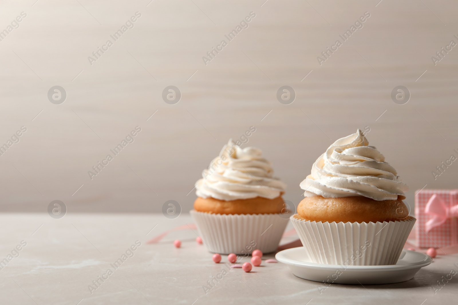 Photo of Delicious cupcakes decorated with cream on light grey table. Space for text