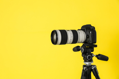 Photo of Modern professional video camera on yellow background