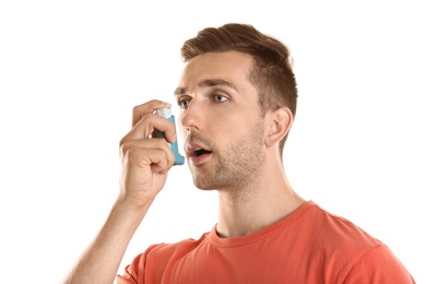 Photo of Young man with asthma using inhaler on white background