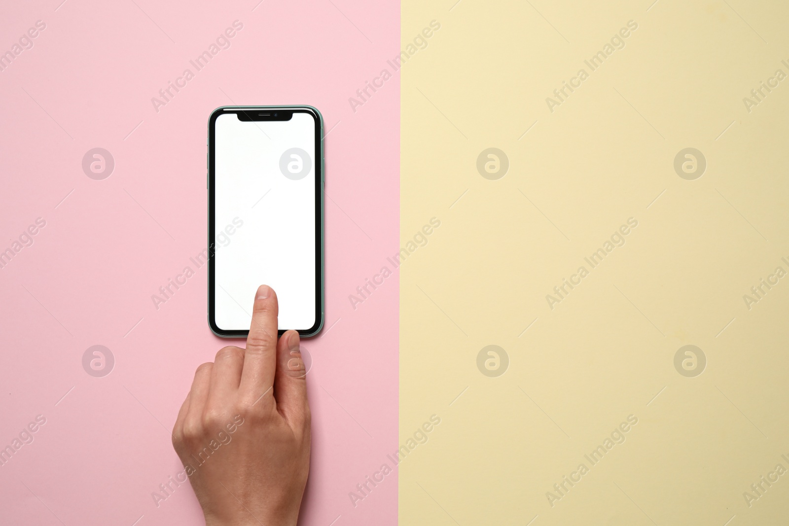 Photo of MYKOLAIV, UKRAINE - JULY 07, 2020: Woman using iPhone 11 on color background, top view. Mockup for design