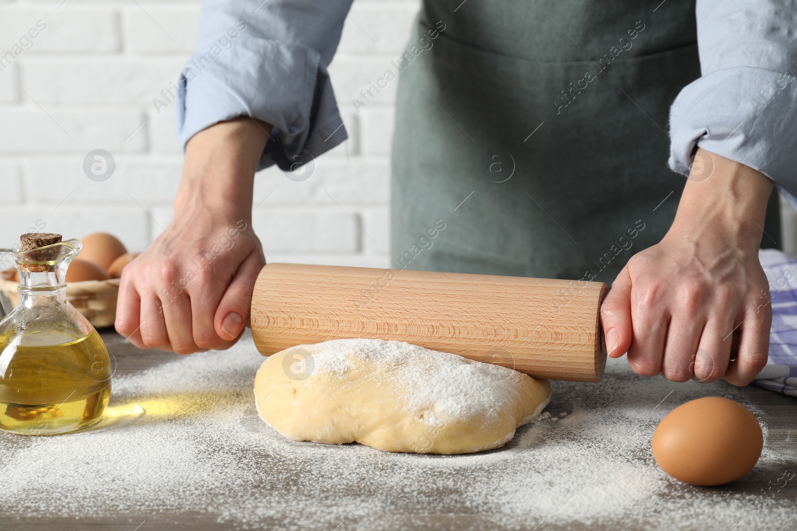 Photo of Woman rolling raw dough at table, closeup