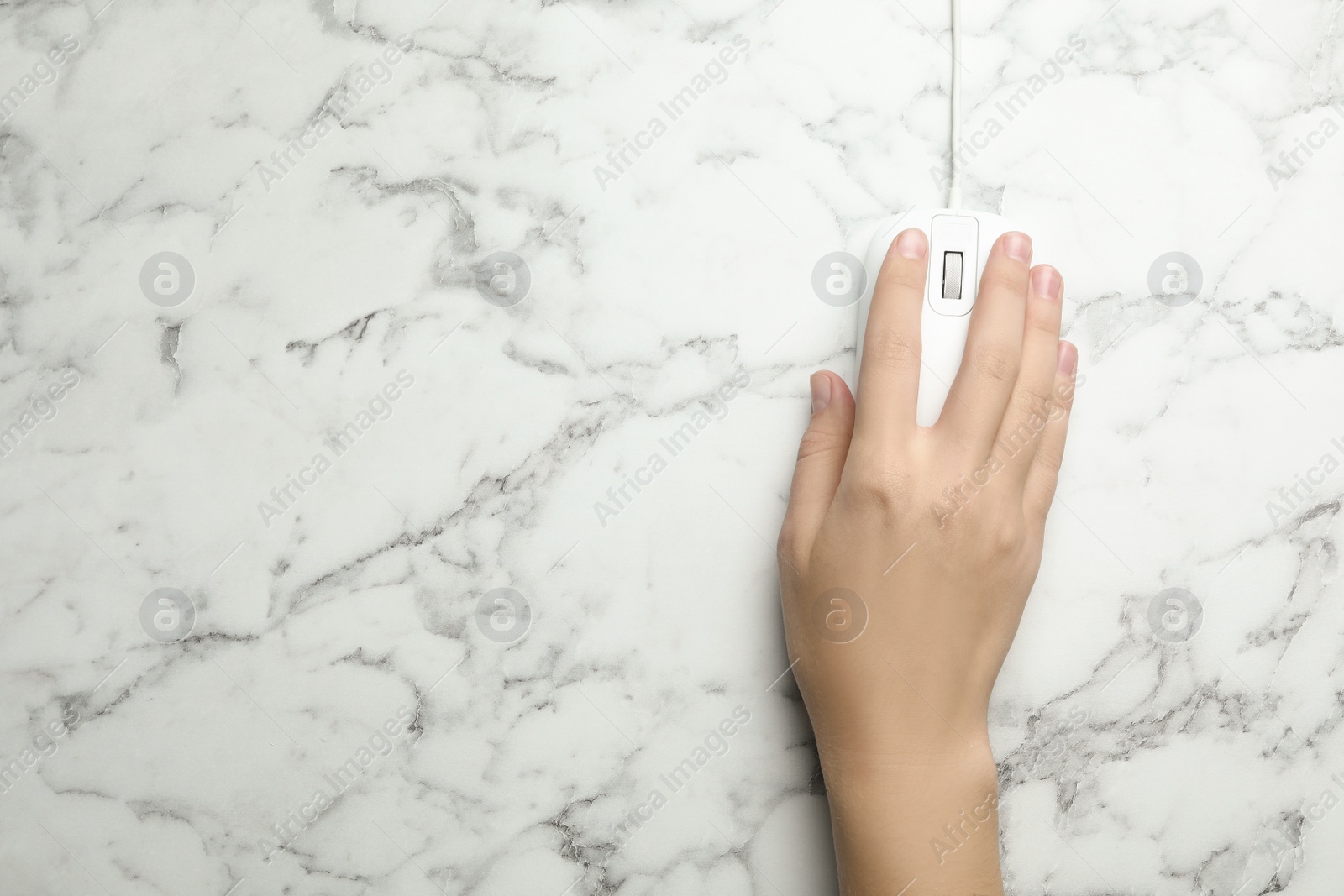 Photo of Woman using wired computer mouse on marble table, top view. Space for text