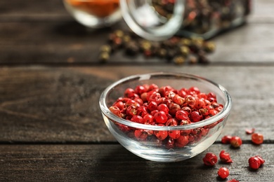 Photo of Glass bowl with red peppercorns on wooden table