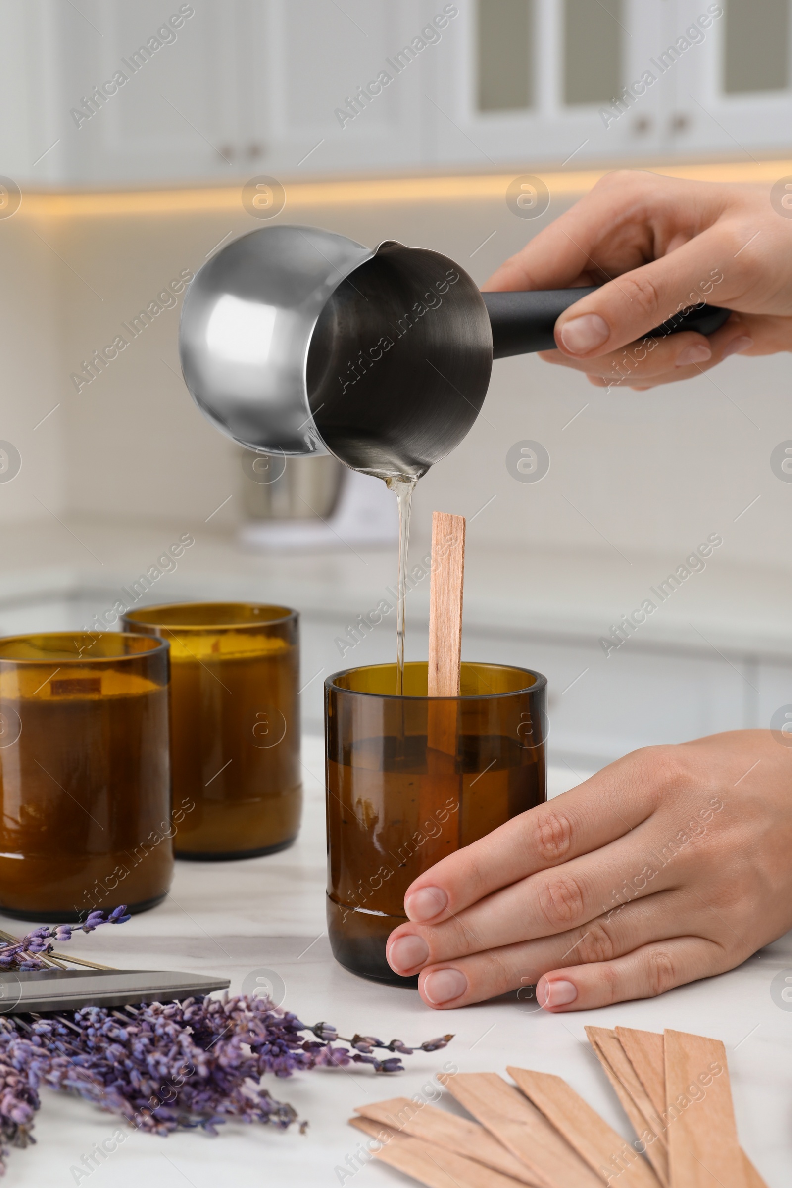 Photo of Woman making homemade candle at table in kitchen, closeup