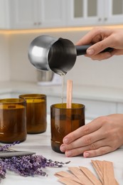 Woman making homemade candle at table in kitchen, closeup