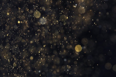Photo of Golden glitter with bokeh effect on dark background
