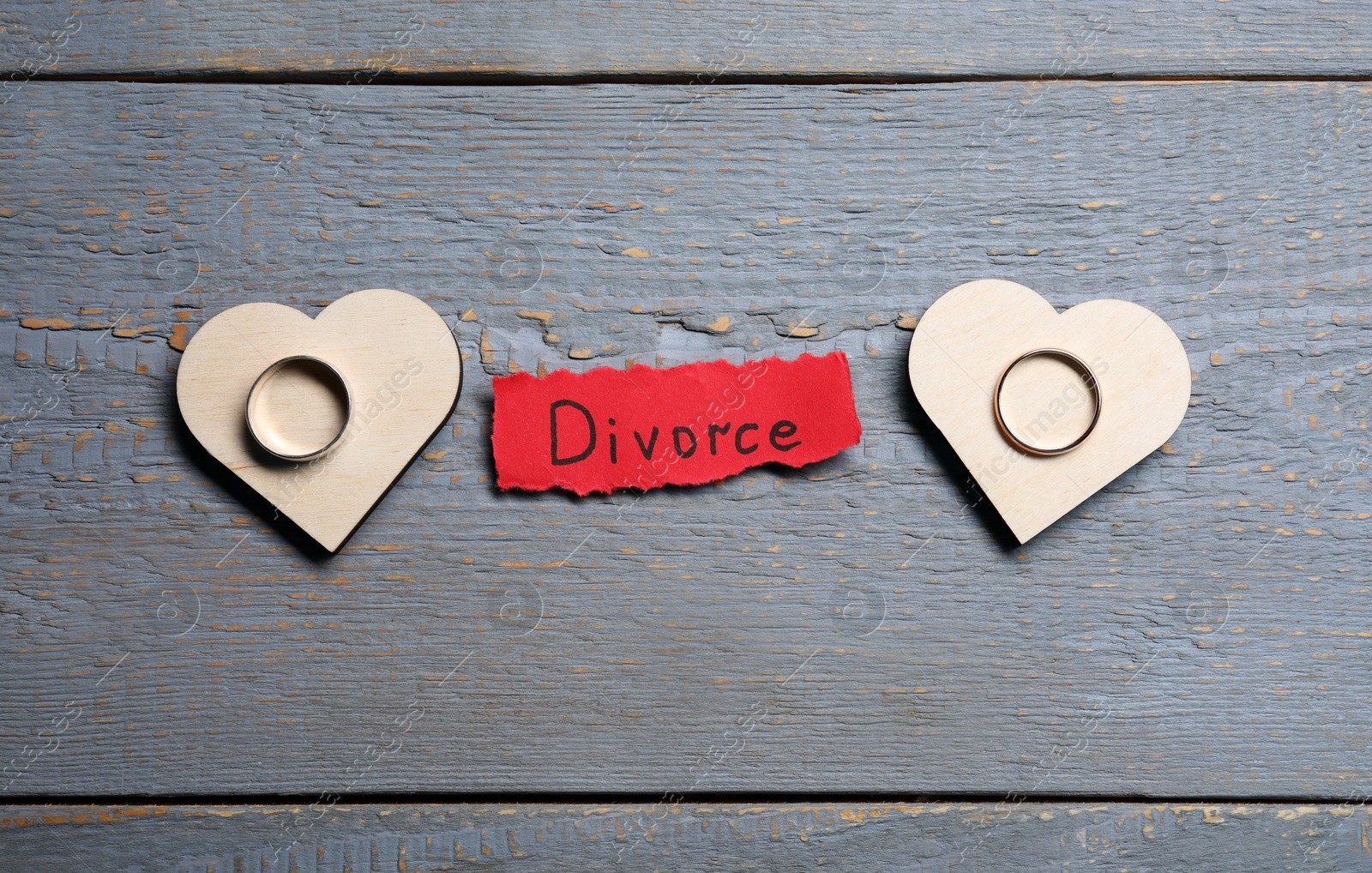 Photo of Paper sheet with word Divorce and wedding rings on grey wooden table, flat lay