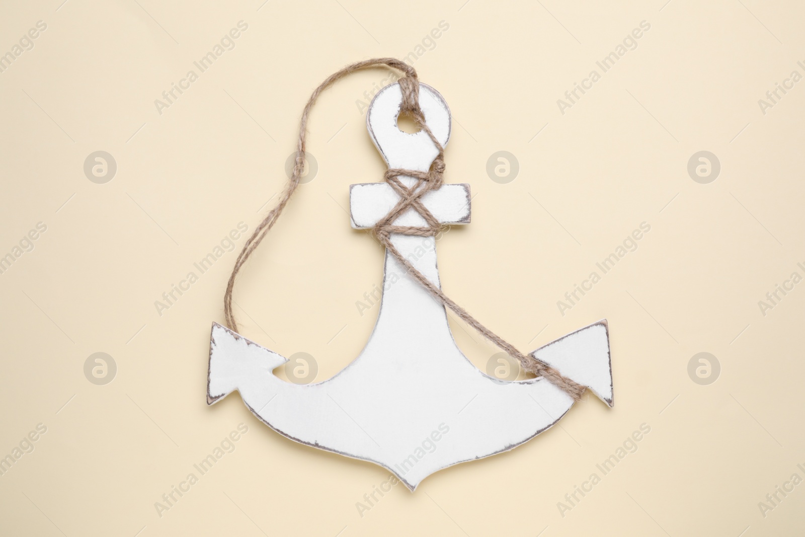 Photo of White anchor with hemp rope on beige background, top view