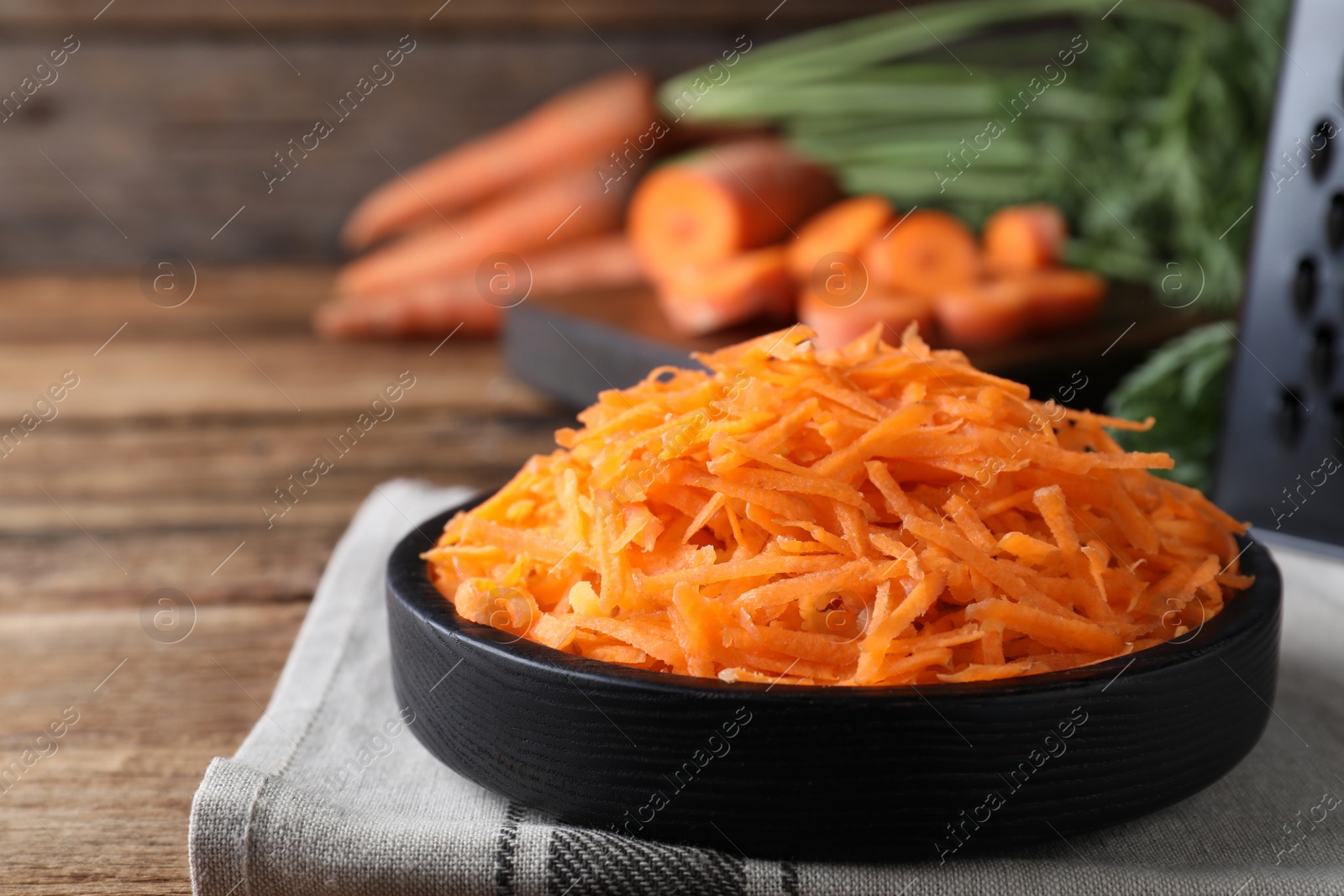 Photo of Grated carrot in plate on wooden table, closeup