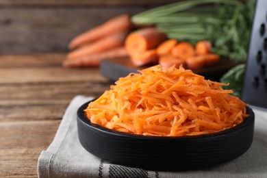 Grated carrot in plate on wooden table, closeup