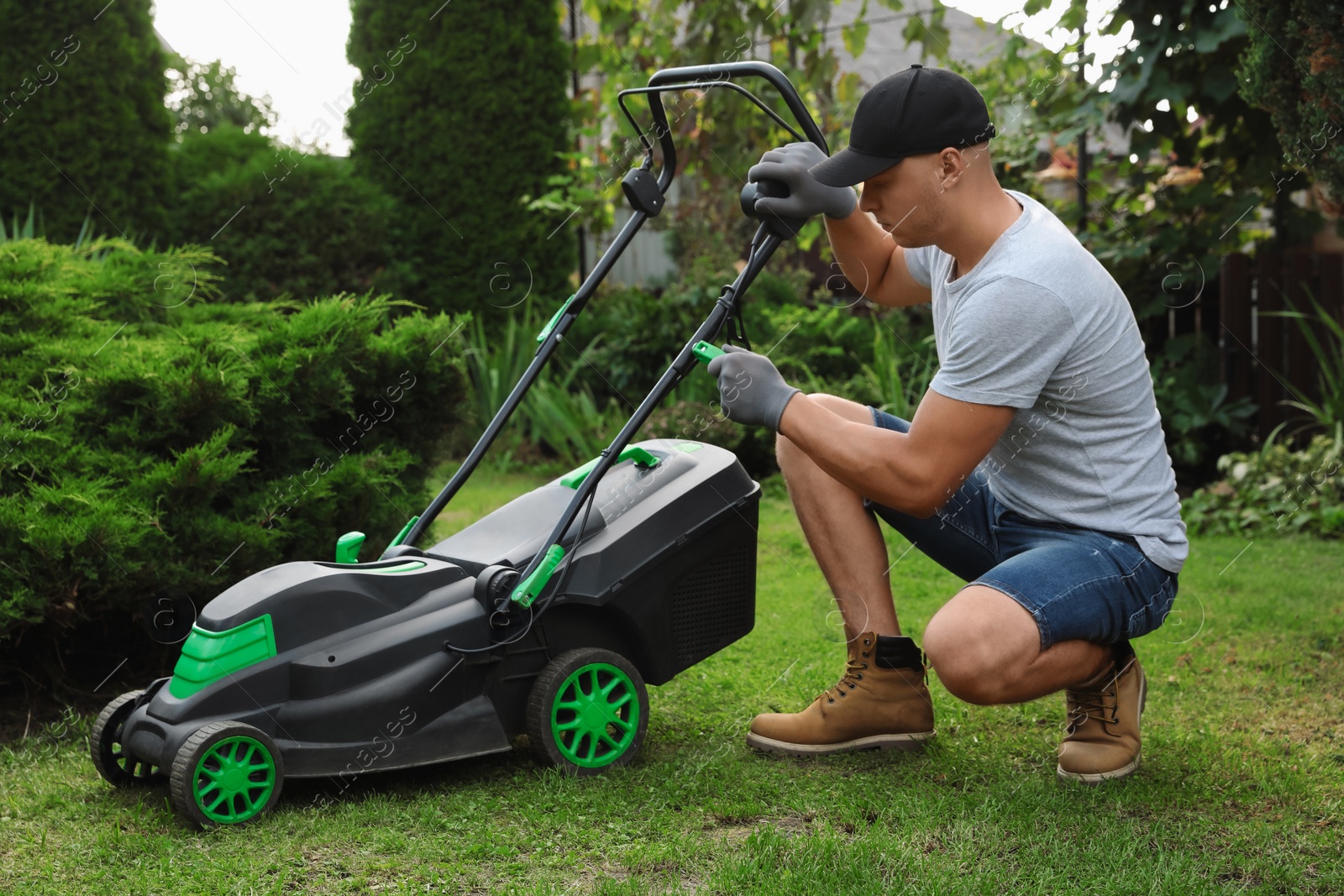 Photo of Young man fixing lawn mower in garden