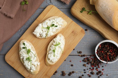 Photo of Bread with cottage cheese and microgreens on grey wooden table, flat lay
