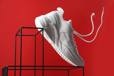 Photo of Stylish presentation of one sneaker on red background