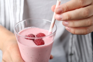 Image of Woman with glass of tasty raspberry smoothie, closeup