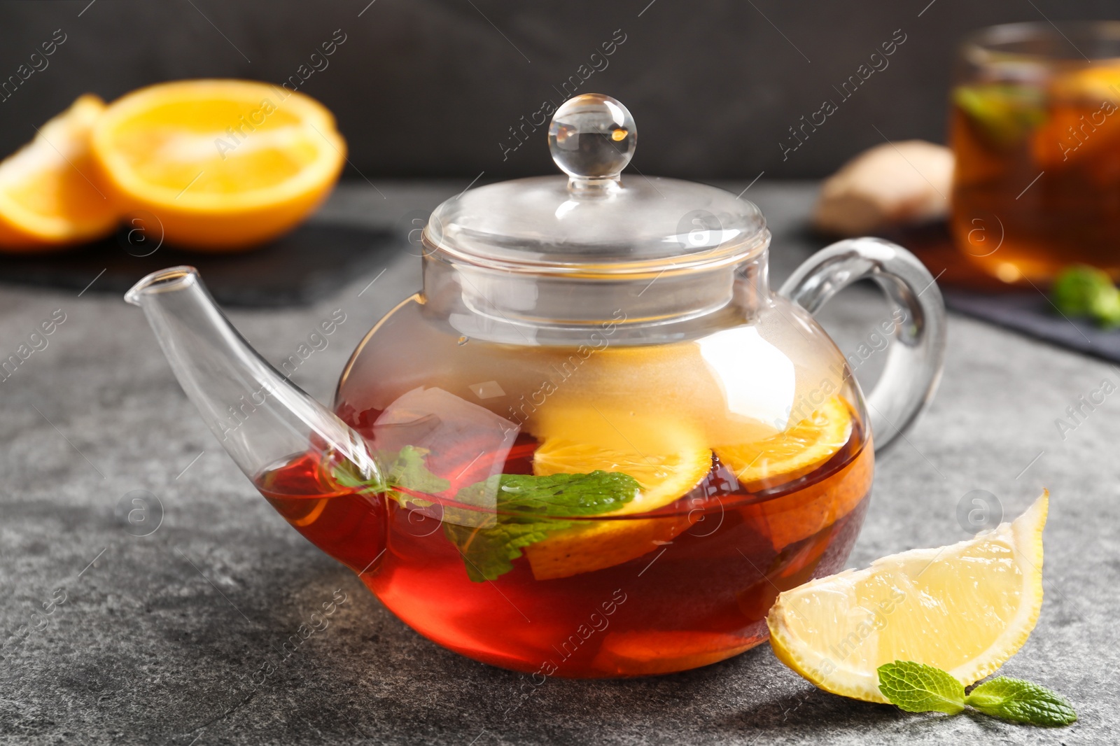 Photo of Hot tea with lemon slices and mint on grey table