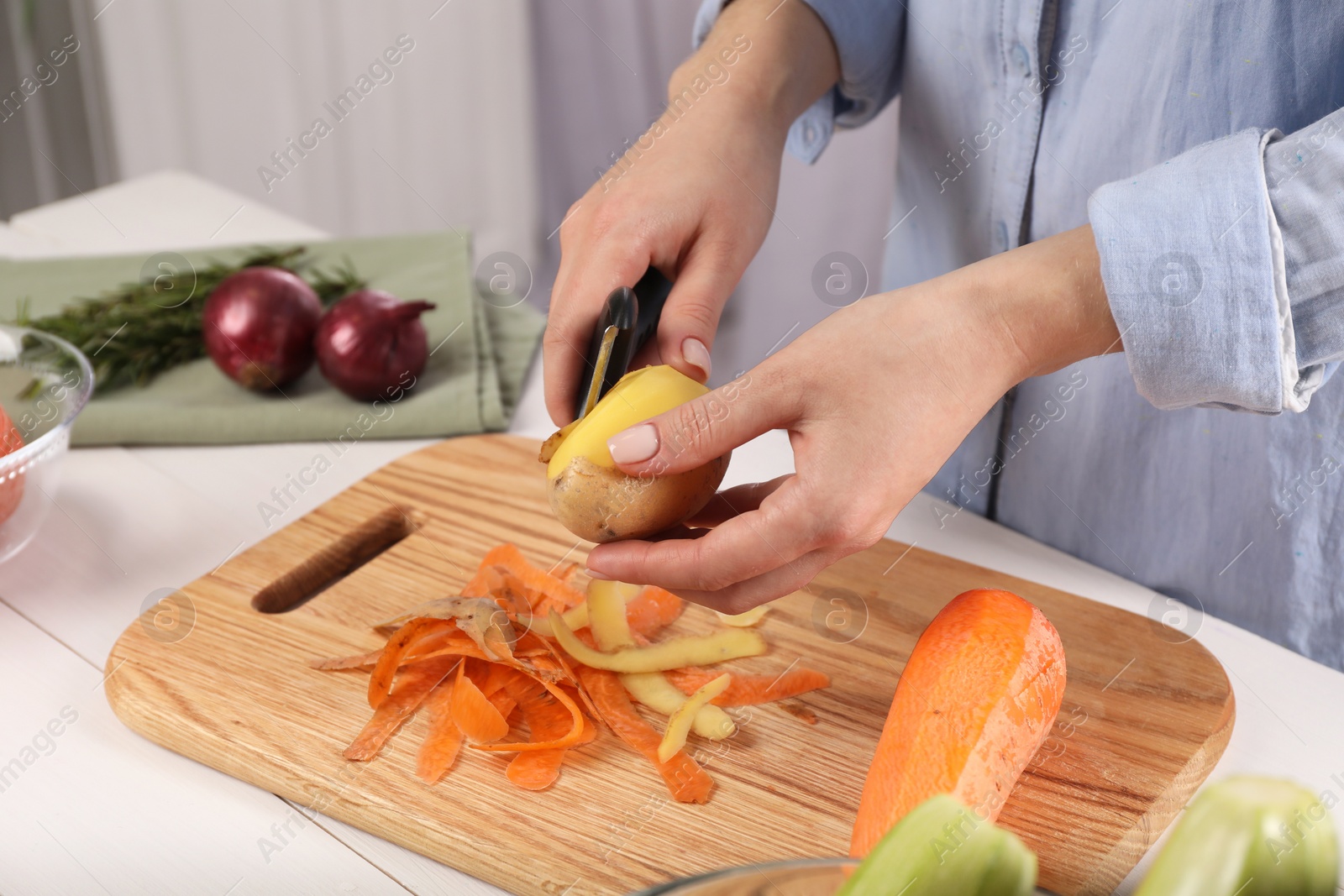 Photo of Woman peeling fresh potato at table indoors, closeup