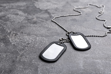 Photo of Blank military ID tags on grey stone surface, space for text