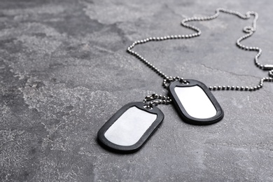 Blank military ID tags on grey stone surface, space for text