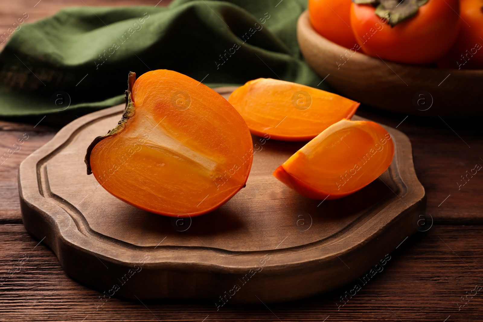 Photo of Pieces of delicious ripe juicy persimmons on wooden table