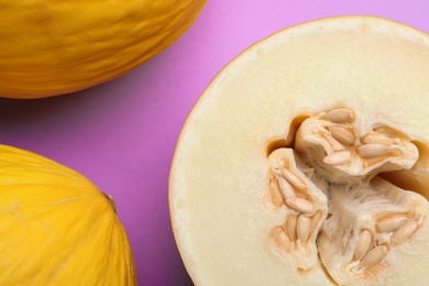 Photo of Ripe tasty melons on violet background, flat lay. Closeup