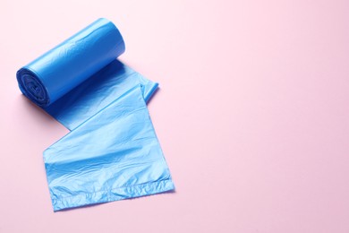 Roll of turquoise garbage bags on pink background, space for text. Cleaning supplies