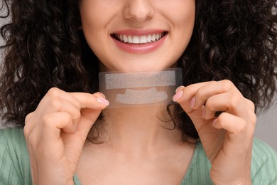 Photo of Young woman holding teeth whitening strips, closeup