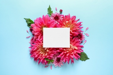 Flat lay composition with beautiful dahlia flowers and blank card on color background