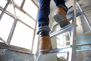 Professional constructor on ladder in old building, closeup