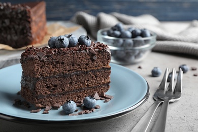 Photo of Delicious fresh chocolate cake served with blueberries on grey table