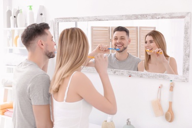 Photo of Young couple brushing teeth together in bathroom