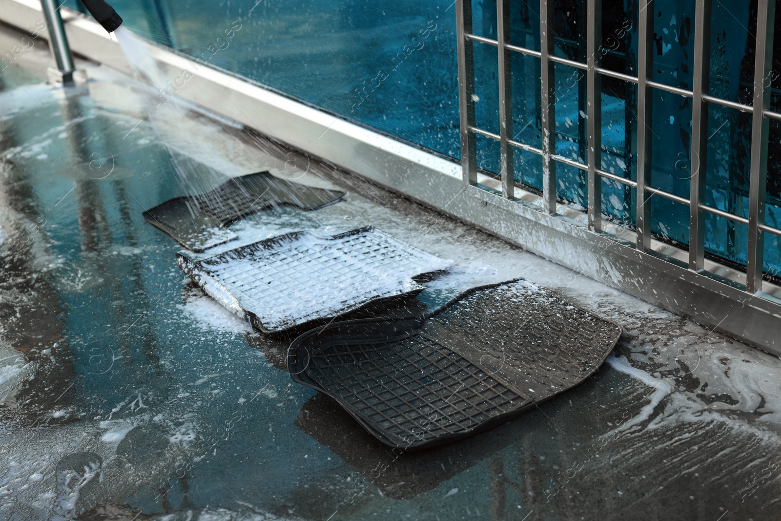 Photo of Cleaning auto mats with high pressure foam jet at car wash, closeup