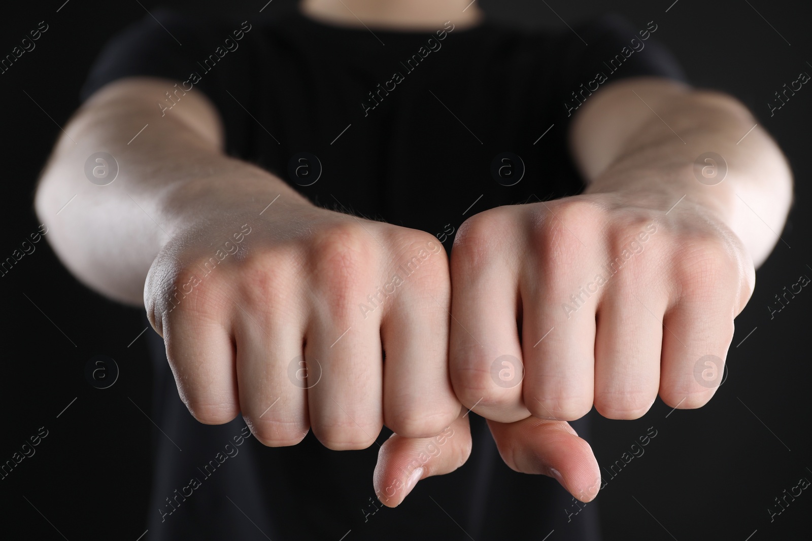 Photo of Man showing fists with space for tattoo on black background, closeup