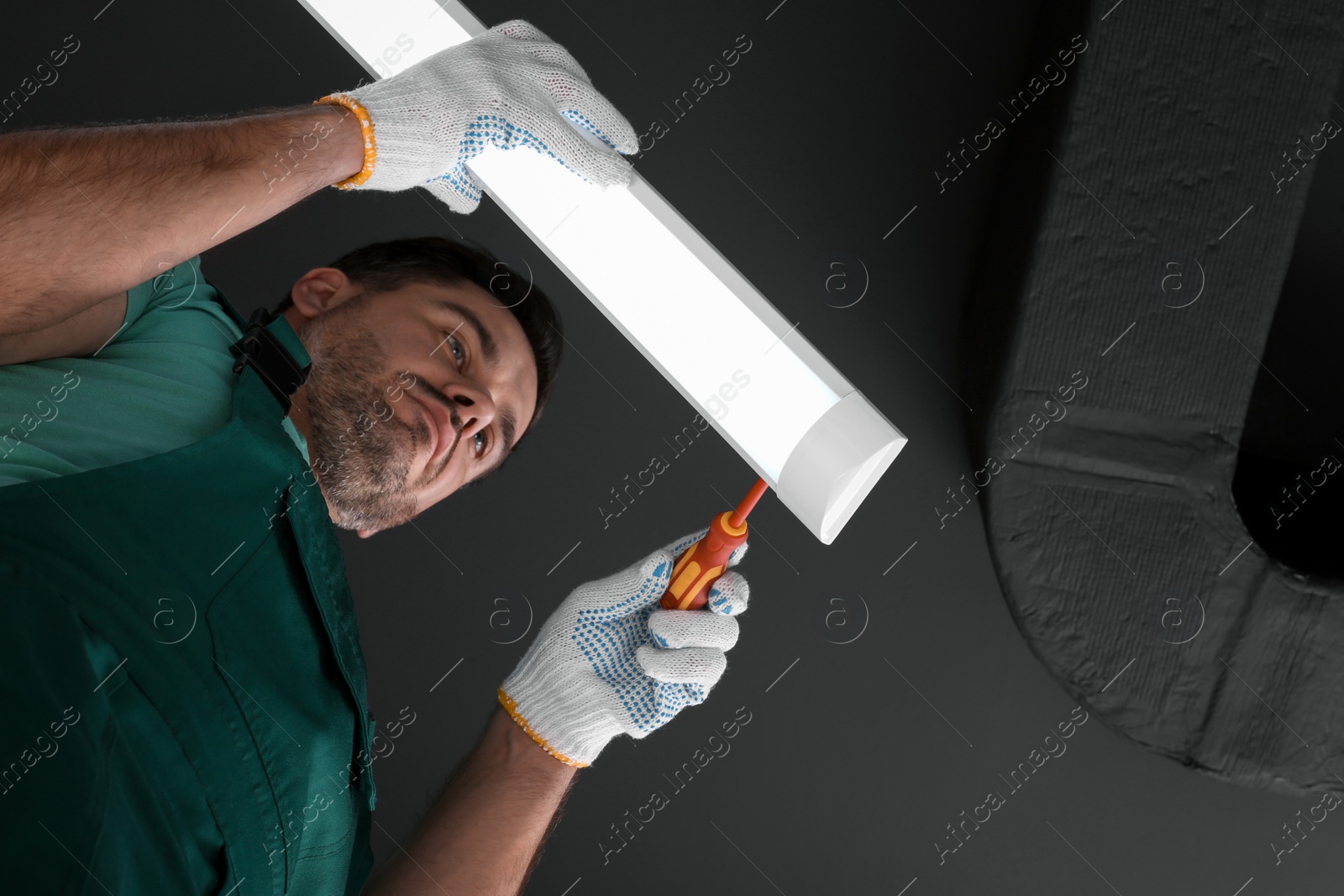 Photo of Ceiling light. Electrician installing led linear lamp indoors, bottom view